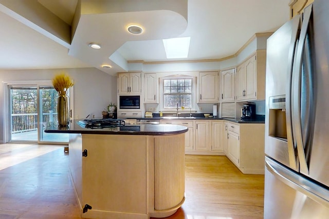 kitchen with sink, a skylight, a center island, appliances with stainless steel finishes, and a raised ceiling