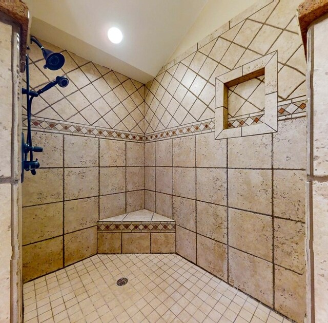 bathroom featuring tiled shower and lofted ceiling