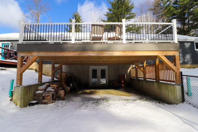 snow covered property with a wooden deck and french doors