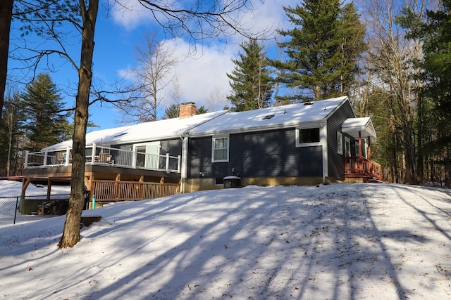 snow covered back of property with a wooden deck