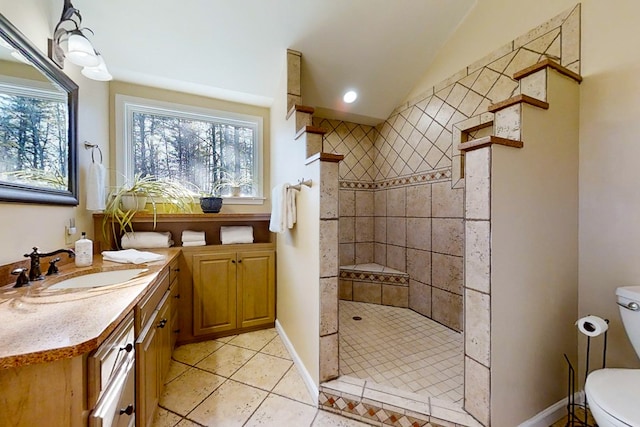 bathroom featuring lofted ceiling, toilet, a tile shower, vanity, and tile patterned flooring