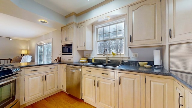 kitchen with appliances with stainless steel finishes, sink, light wood-type flooring, and kitchen peninsula