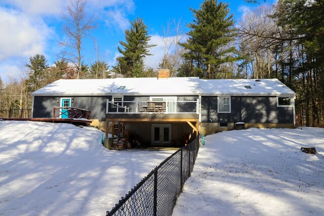 snow covered back of property featuring a wooden deck and french doors