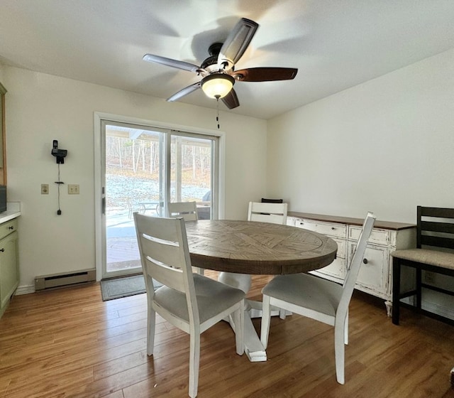 dining space featuring a baseboard heating unit, ceiling fan, and light hardwood / wood-style flooring