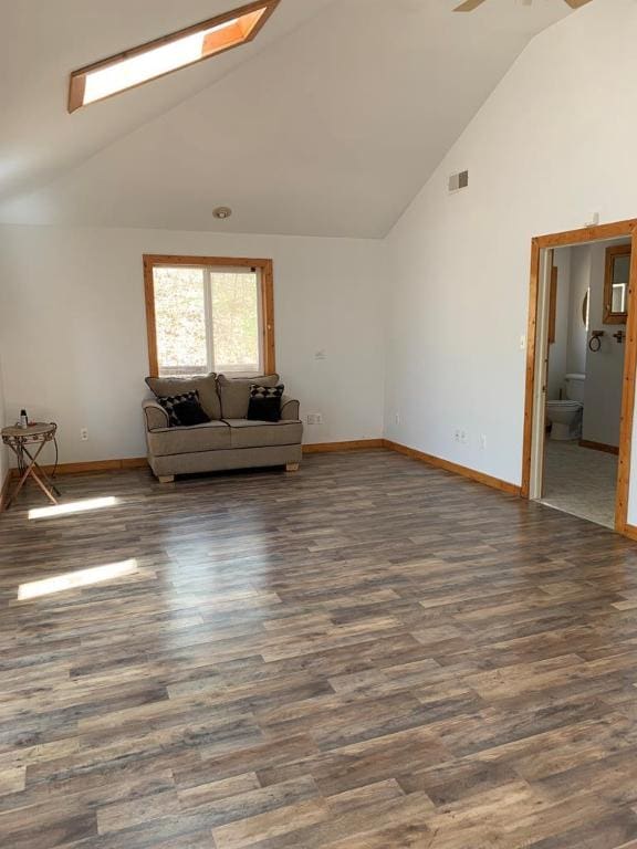 unfurnished living room with ceiling fan, dark hardwood / wood-style flooring, a skylight, and high vaulted ceiling