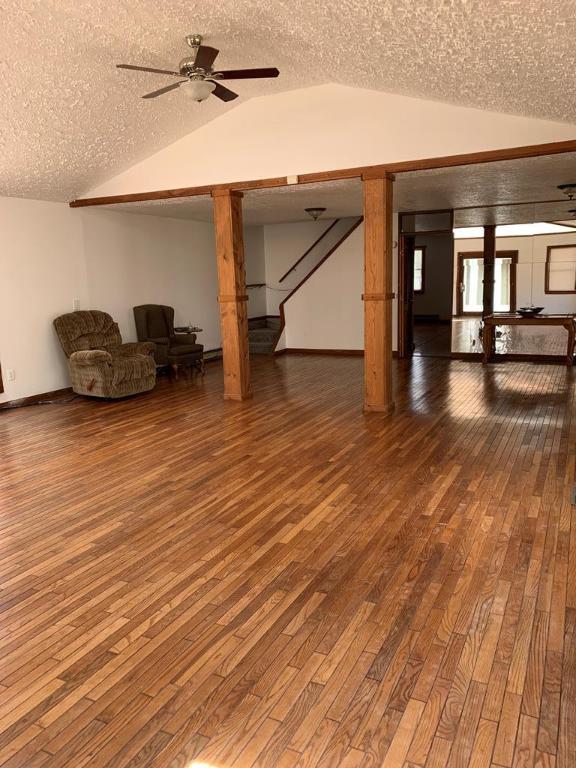 interior space featuring ceiling fan, wood-type flooring, and a textured ceiling