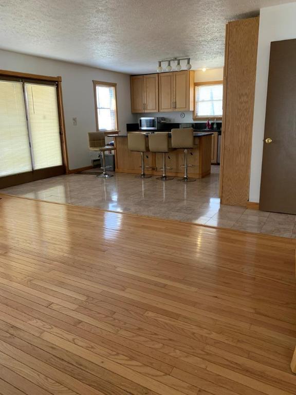 kitchen with light wood-type flooring, a textured ceiling, and a kitchen bar