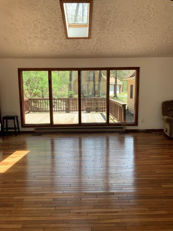 unfurnished room with plenty of natural light, dark wood-type flooring, and a skylight