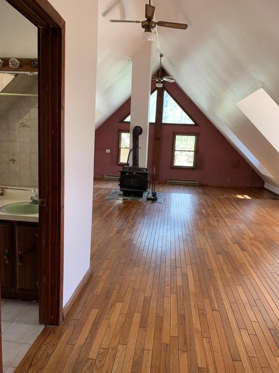 additional living space featuring baseboard heating, lofted ceiling, sink, and light wood-type flooring