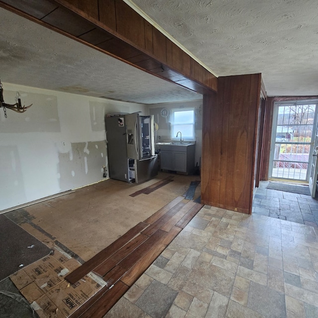 interior space with sink, a textured ceiling, and wood walls