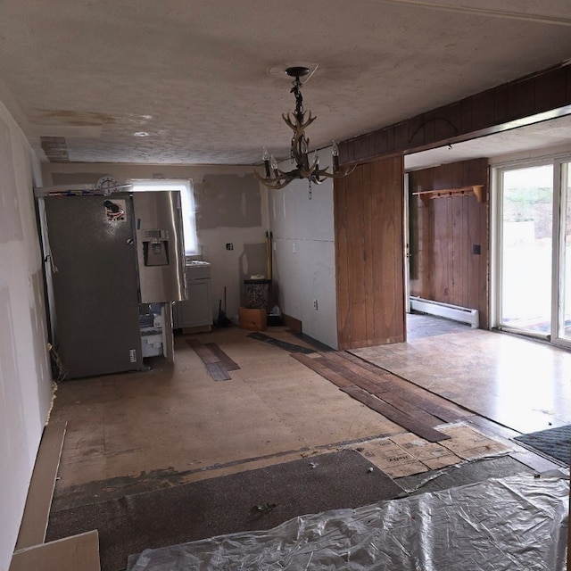 unfurnished dining area with a baseboard heating unit and a notable chandelier