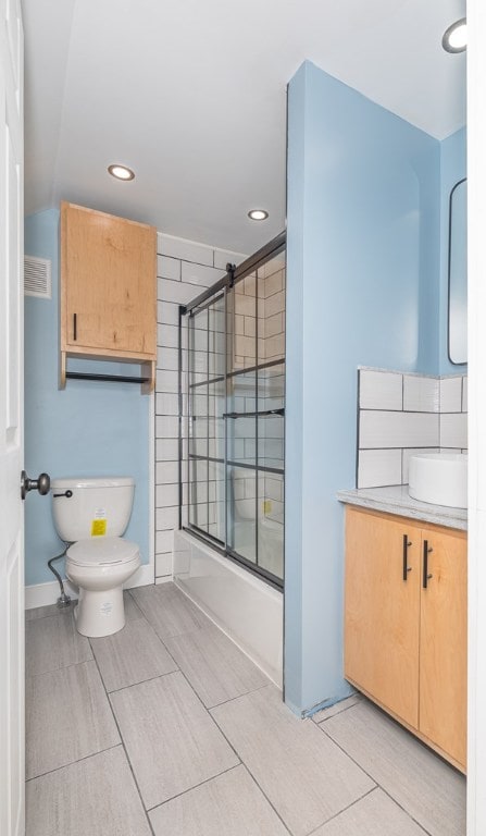 full bathroom featuring vanity, enclosed tub / shower combo, and toilet