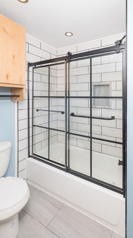 bathroom featuring bath / shower combo with glass door and toilet