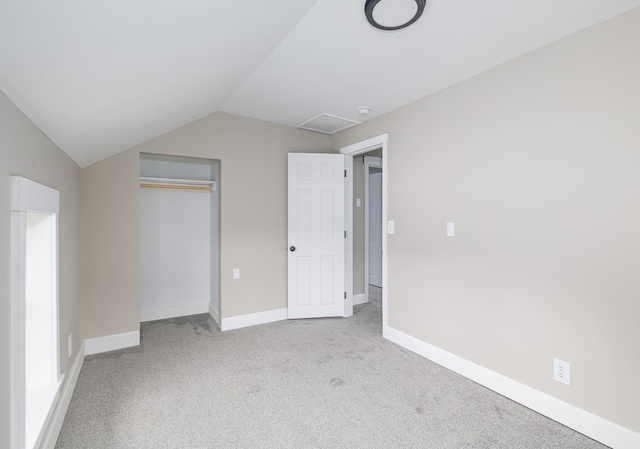 unfurnished bedroom with a closet, lofted ceiling, and light carpet