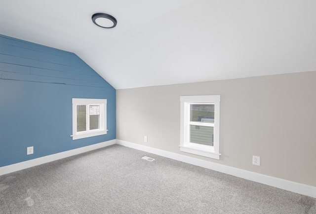 additional living space featuring vaulted ceiling and carpet flooring