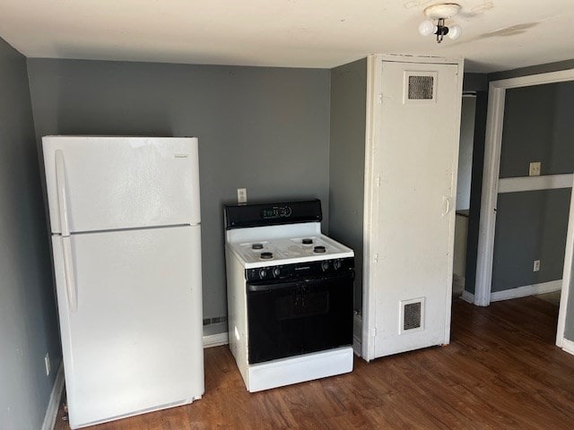 kitchen with white refrigerator, dark hardwood / wood-style flooring, and stove