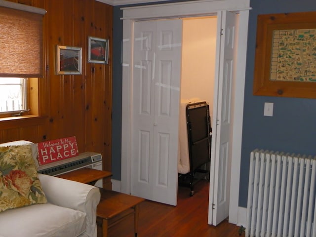 living area featuring radiator heating unit, wooden walls, and hardwood / wood-style floors