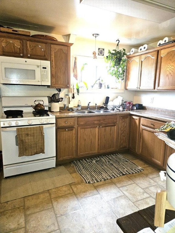 kitchen with pendant lighting, white appliances, and sink