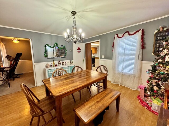 dining space with crown molding, an inviting chandelier, and light hardwood / wood-style flooring