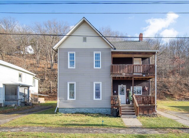 view of property with a balcony and a front yard