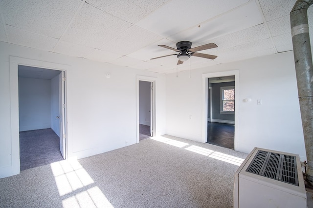 carpeted spare room featuring a drop ceiling and ceiling fan