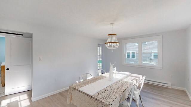 dining room with a barn door, a baseboard heating unit, a chandelier, and light hardwood / wood-style flooring