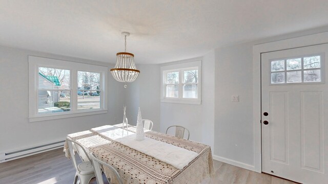 dining room with a baseboard heating unit, a notable chandelier, and light wood-type flooring