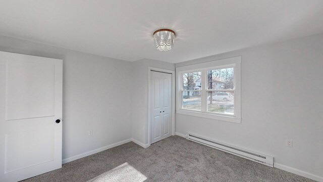 unfurnished bedroom with baseboard heating, light colored carpet, and a closet