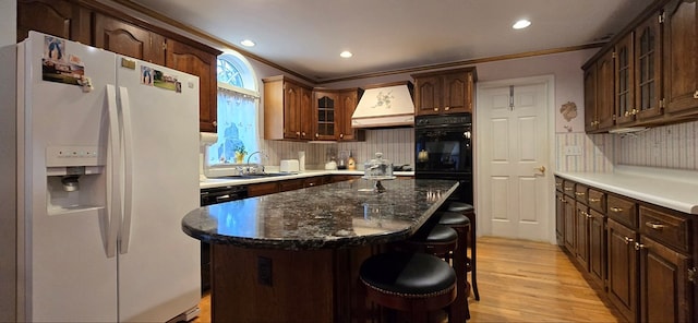 kitchen featuring custom range hood, white fridge with ice dispenser, a kitchen island, decorative backsplash, and light wood-type flooring