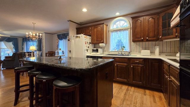 kitchen with a healthy amount of sunlight, white refrigerator with ice dispenser, a kitchen island, and light wood-type flooring