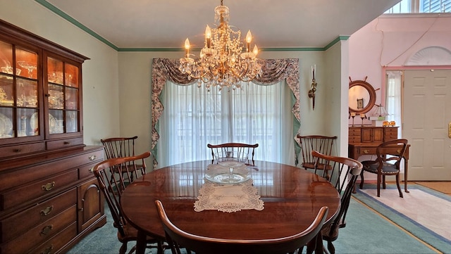 dining space with an inviting chandelier, ornamental molding, and carpet