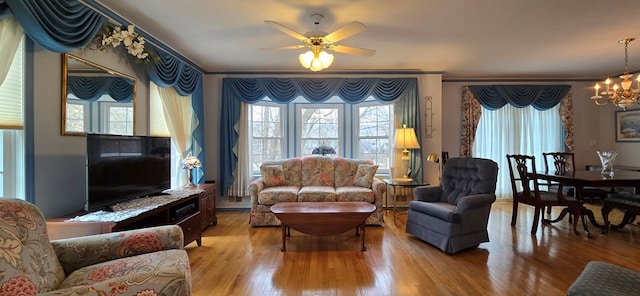 living room featuring ornamental molding, ceiling fan with notable chandelier, and light hardwood / wood-style flooring