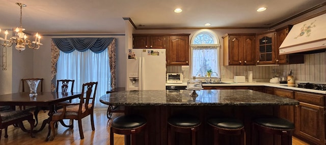 kitchen with a kitchen island, sink, white fridge with ice dispenser, and black electric stovetop