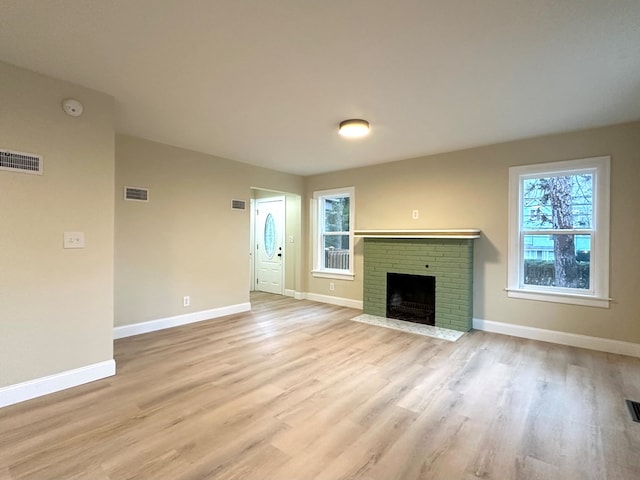 unfurnished living room featuring a brick fireplace and light hardwood / wood-style floors