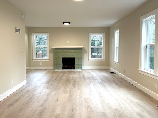 unfurnished living room featuring a brick fireplace and light wood-type flooring