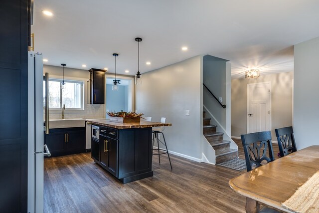 kitchen with backsplash, a kitchen breakfast bar, dark hardwood / wood-style flooring, hanging light fixtures, and a center island