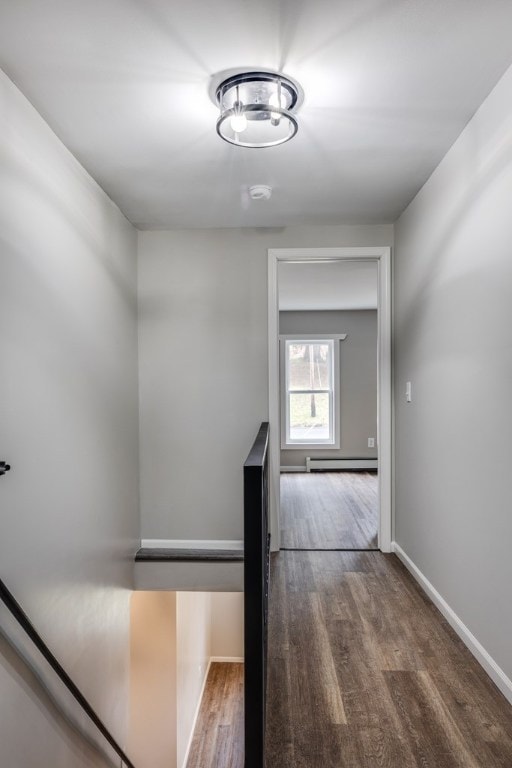 hallway with dark hardwood / wood-style floors and a baseboard heating unit