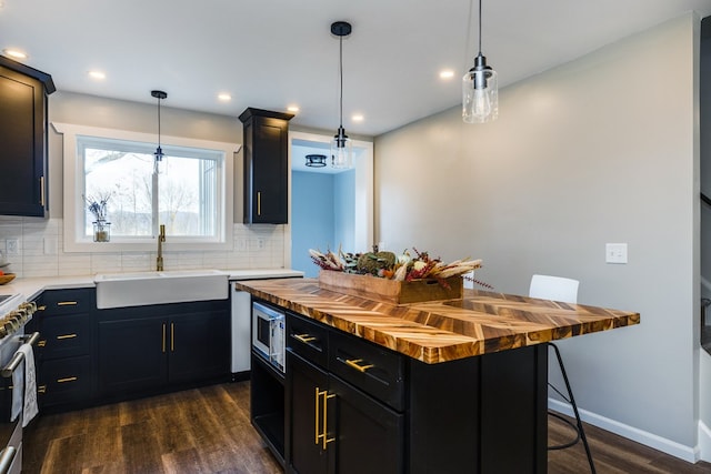 kitchen with sink, wooden counters, hanging light fixtures, a kitchen breakfast bar, and a center island