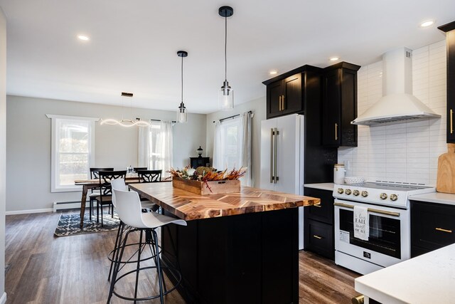 kitchen with wood counters, wall chimney exhaust hood, decorative light fixtures, a center island, and electric range