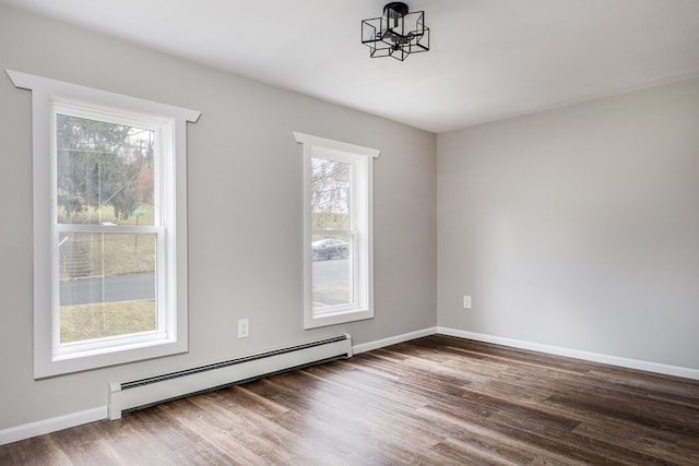 unfurnished room with plenty of natural light, dark hardwood / wood-style flooring, a chandelier, and a baseboard heating unit