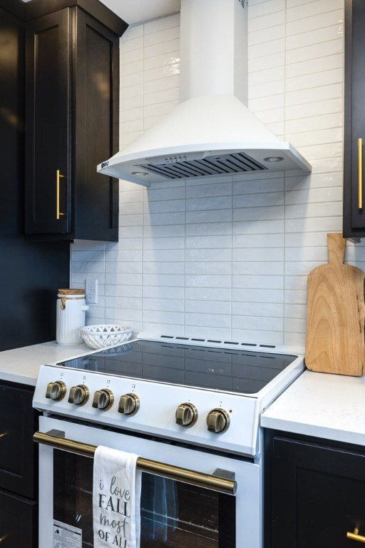 kitchen with tasteful backsplash, wall chimney exhaust hood, and white electric range