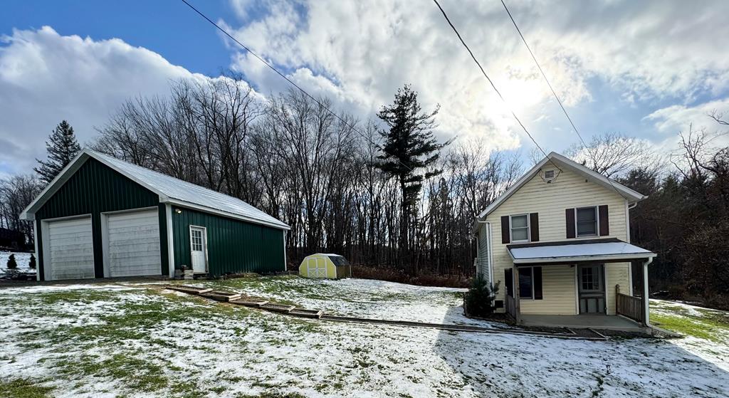 exterior space with covered porch, a garage, and a storage unit