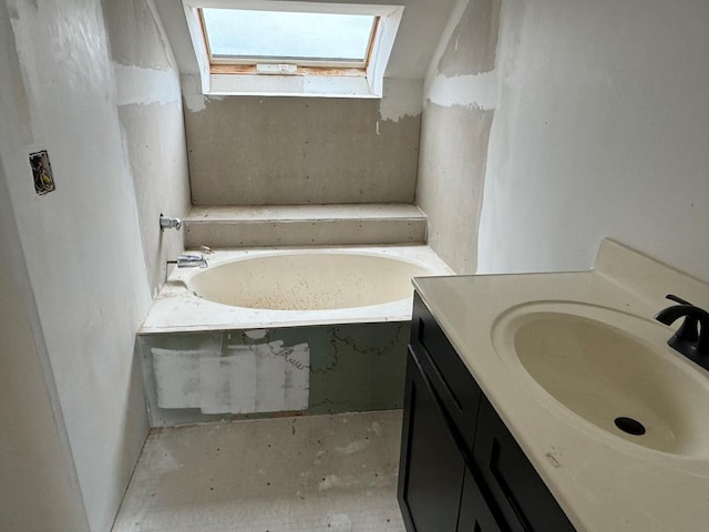 bathroom featuring vanity, a bathing tub, and a skylight