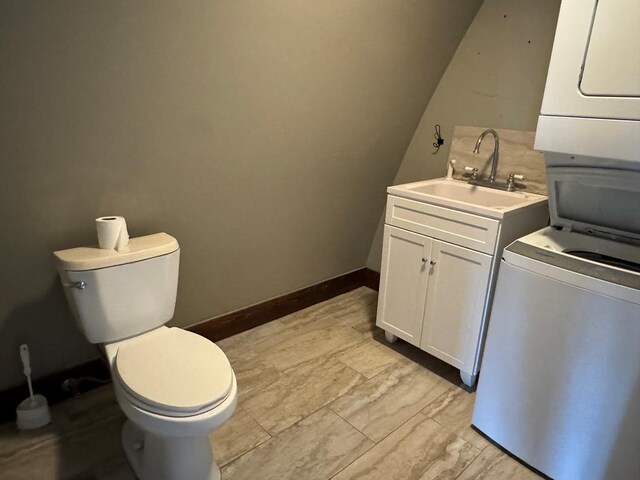 bathroom featuring stacked washer and dryer, vanity, and toilet