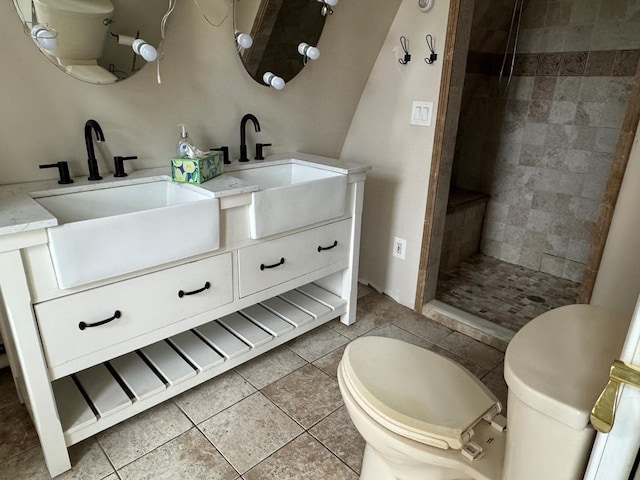 bathroom with vanity, tile patterned flooring, toilet, and tiled shower