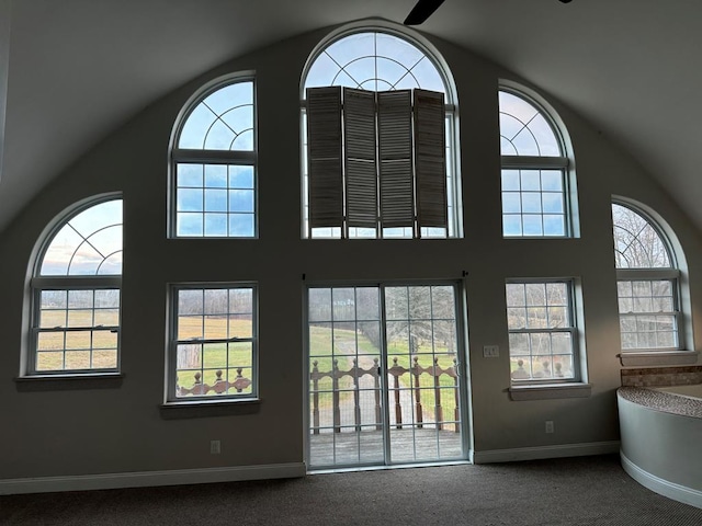 doorway to outside with ceiling fan, carpet flooring, and high vaulted ceiling