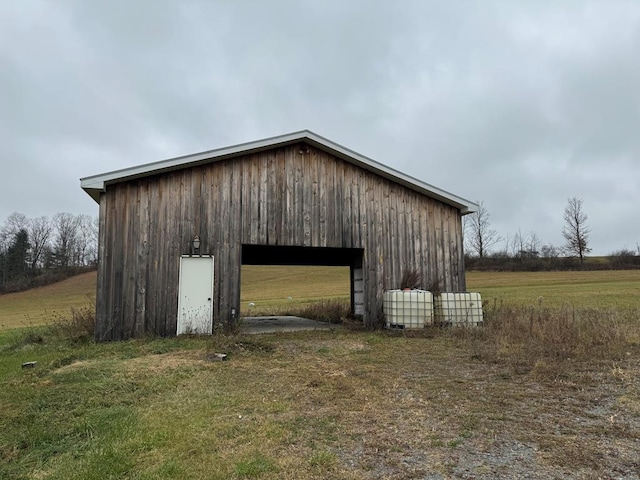 garage with a rural view and a yard