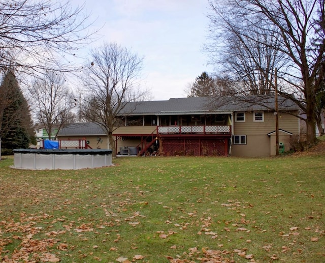 rear view of house with a covered pool and a yard