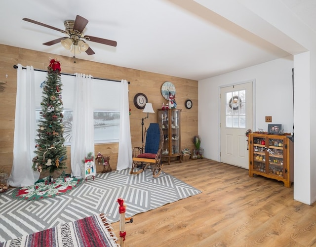 foyer featuring wood walls, ceiling fan, and light wood-type flooring