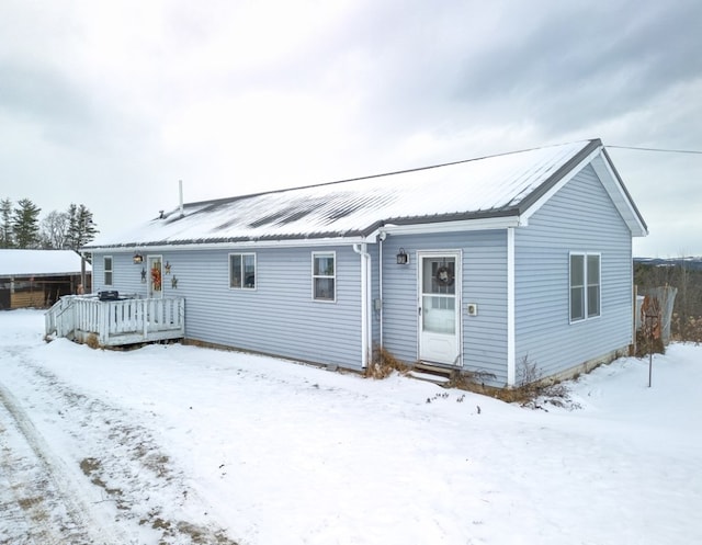 snow covered back of property with a deck